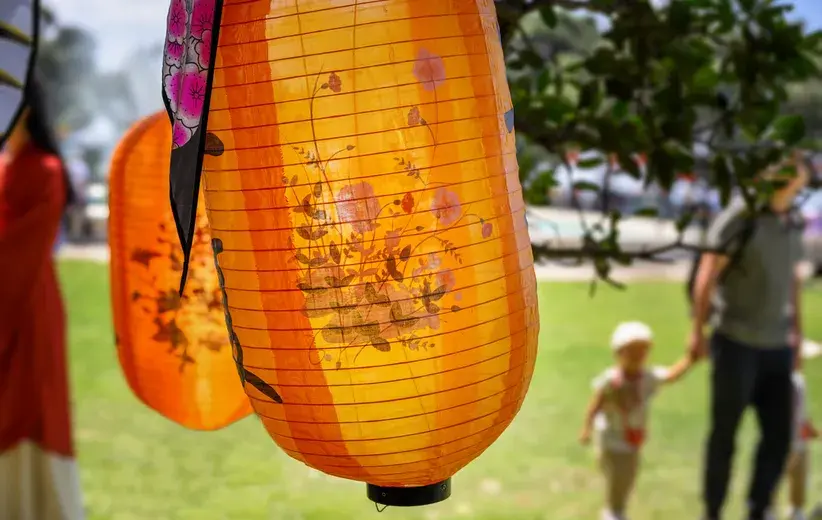 Close-up of vibrant orange paper lanterns with floral designs, symbolising community engagement and connection, representing Now NZ's communication systems tailored for local government.