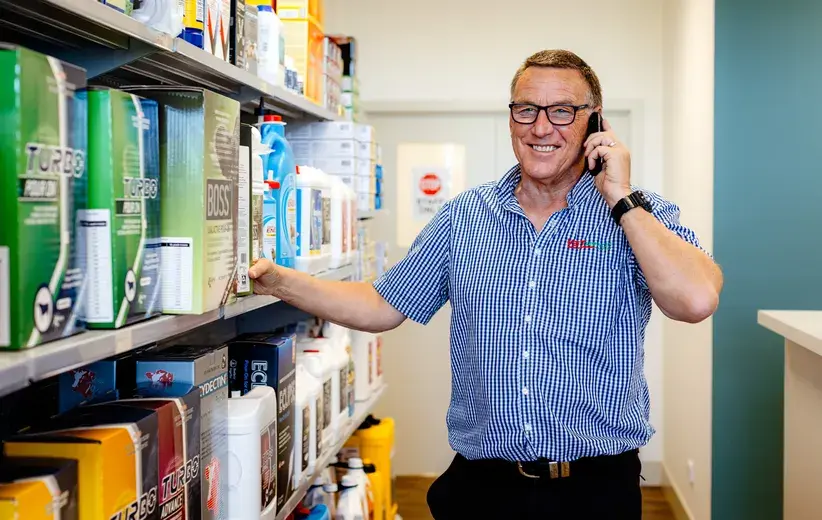 Smiling professional on a phone call in a store aisle filled with products, illustrating Now NZ's scalable telco solutions designed to grow with health and wellness businesses.