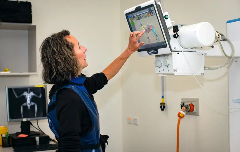 Healthcare professional operating an advanced X-ray machine, representing Now NZ's solutions for seamless connectivity and efficient administration in the health and wellbeing sector.