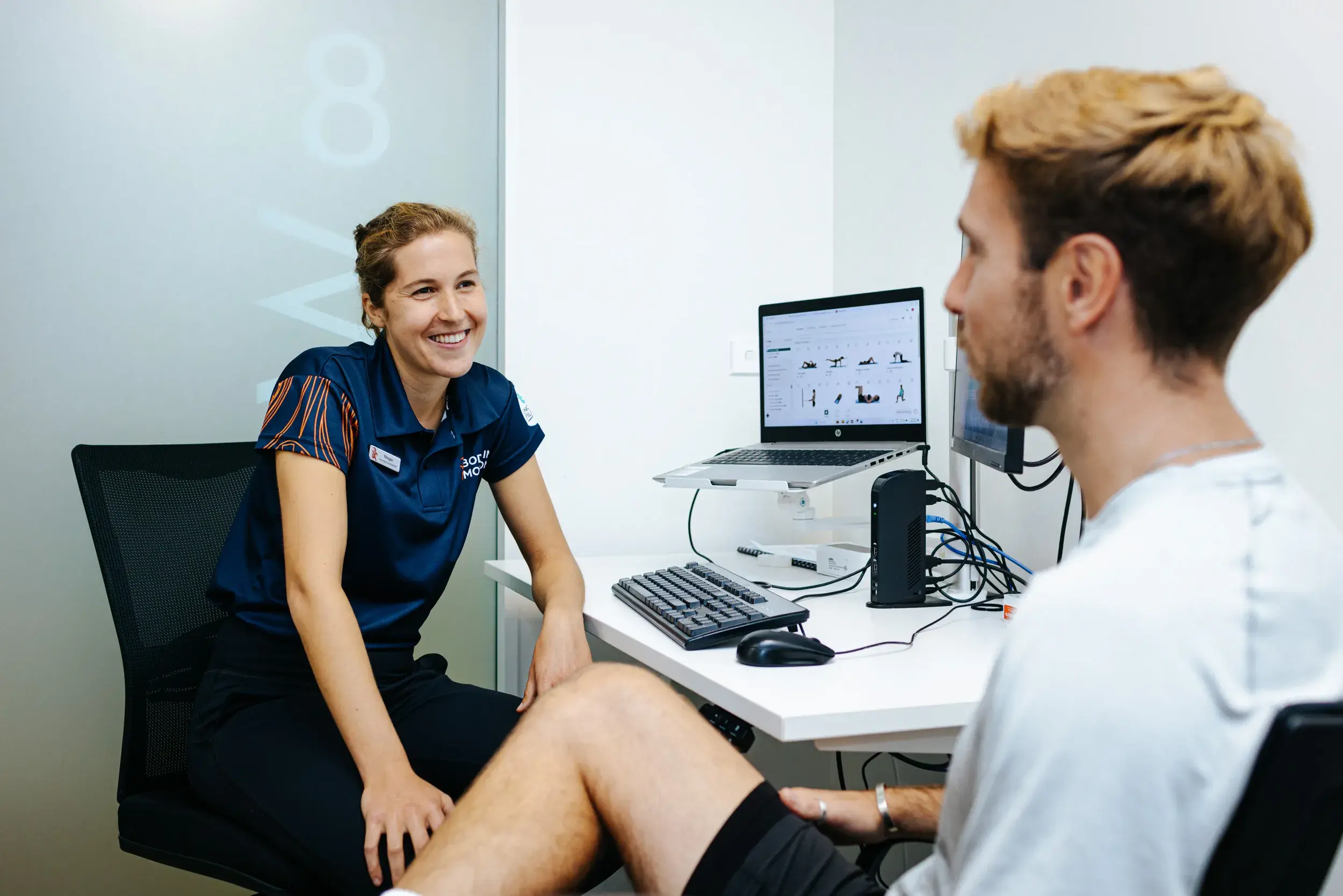 A physiotherapist from Body in Motion consulting with a patient in a clinic, illustrating Now NZ's support in ensuring reliable customer calls for maintaining high service standards and brand reputation.