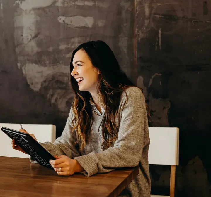 Smiling woman holding a tablet in an office setting, representing the connectivity and flexibility offered by Now Reach for modern Kiwi businesses